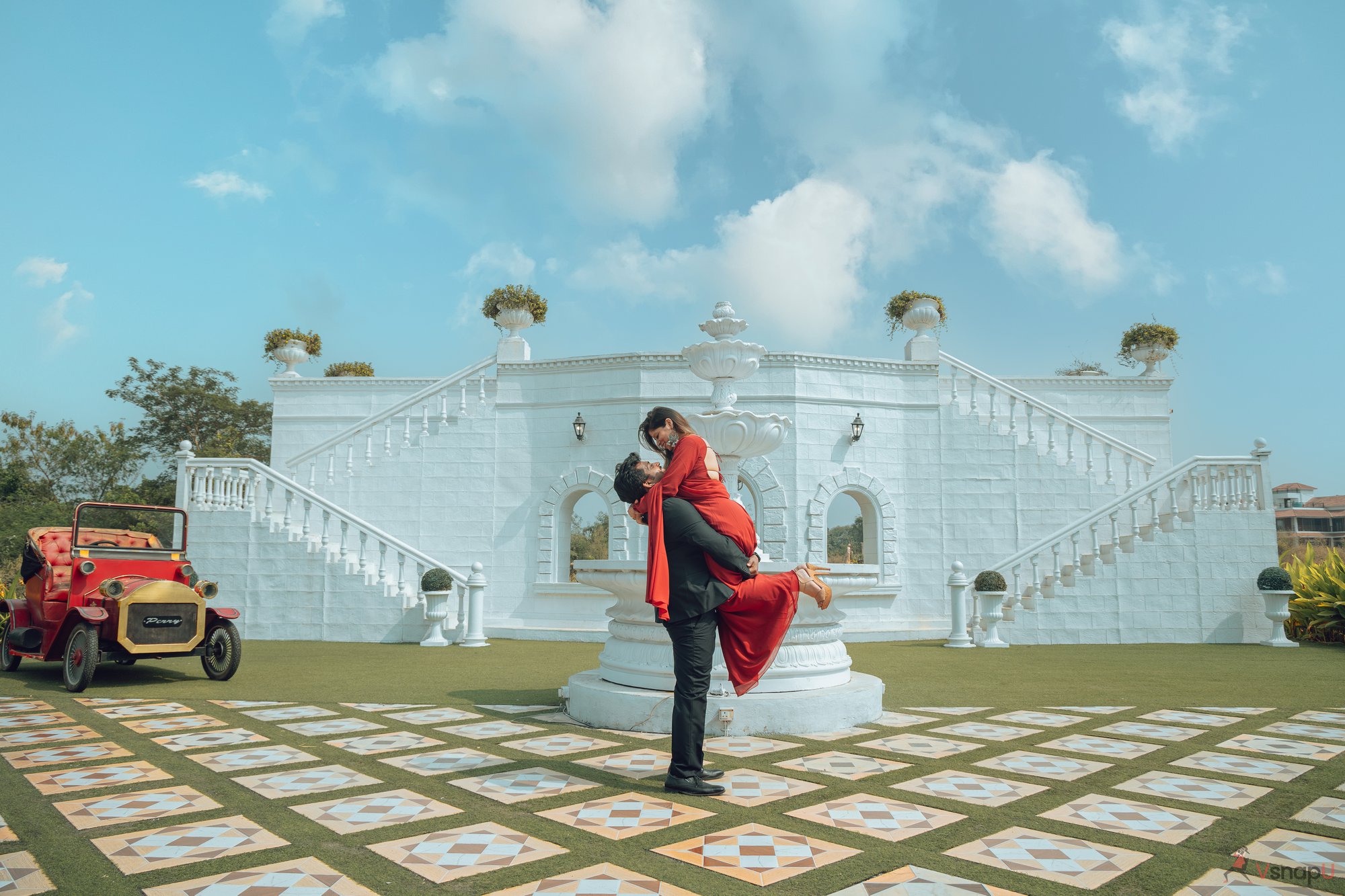 Heritage love story—bride and groom in ethnic wear standing before intricately designed gates.